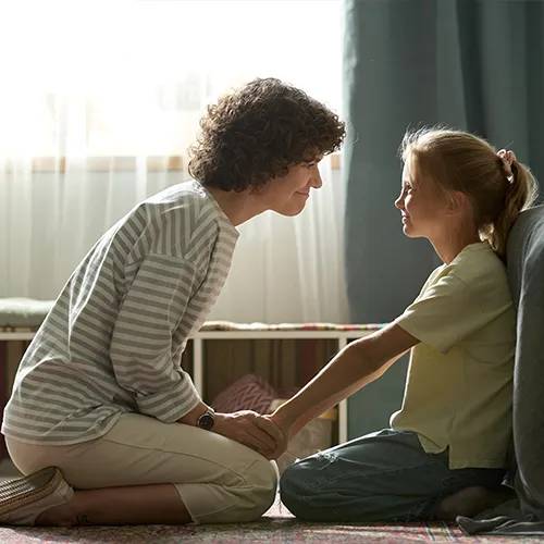 Mother kneeling down and comforting child, and talking about divorce