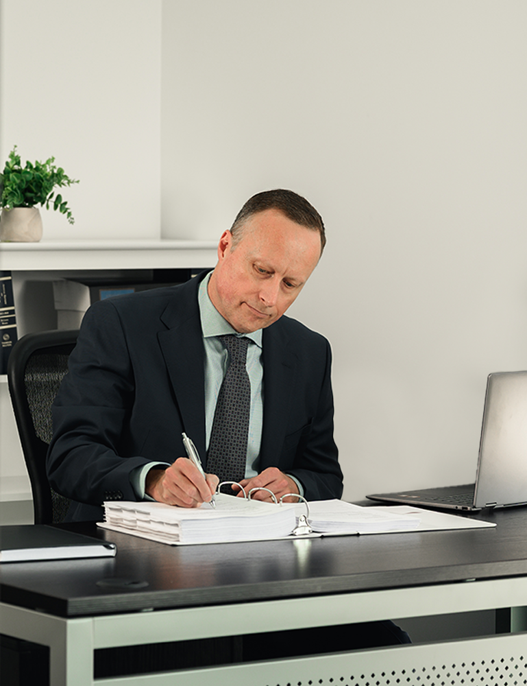 Christopher Bungay, family lawyer at Advantage Family Law, reviewing documents at his desk.