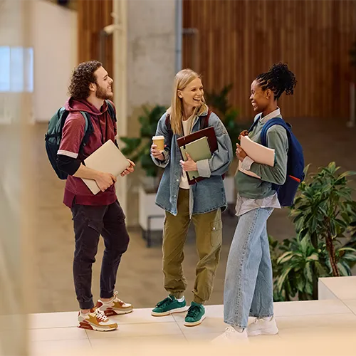 Three university students with backpacks and books chatting on campus, illustrating post-secondary child support in Alberta